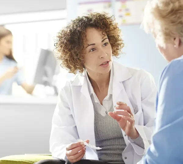 medical professional talking to a patient whilst holding medicine