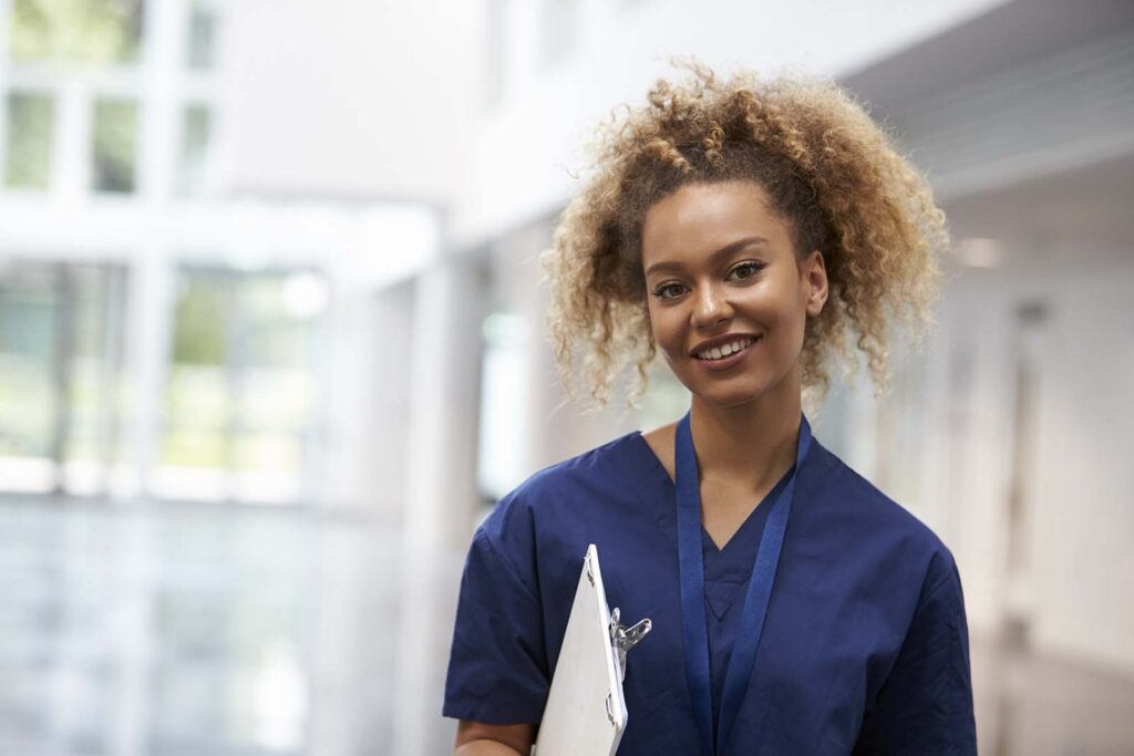 female physiotherapist with a clipboard walking along a coridoor